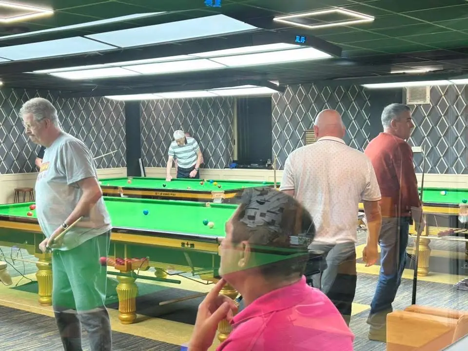 A busy room seen through glass, with players around several tables