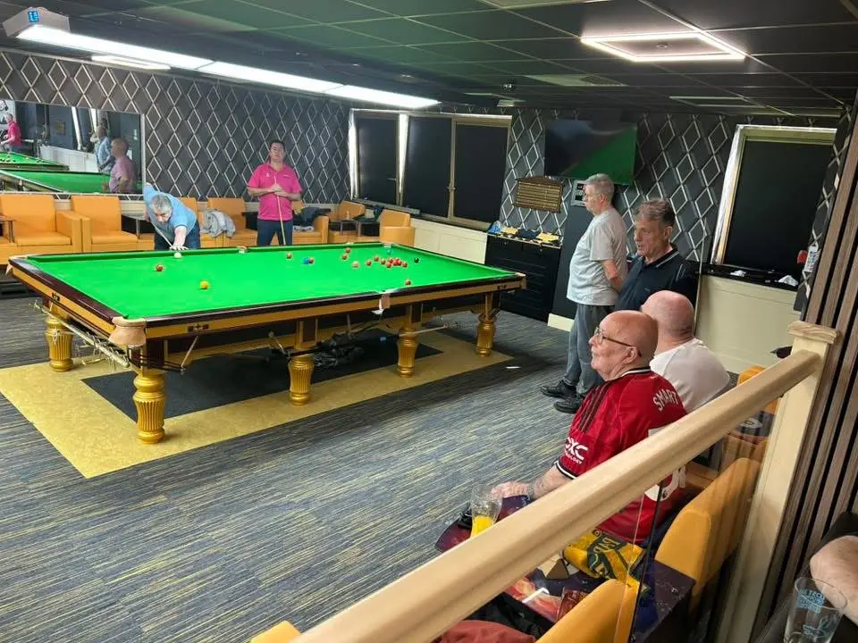 A match in progress viewed over the rail, with spectators seated in the foreground