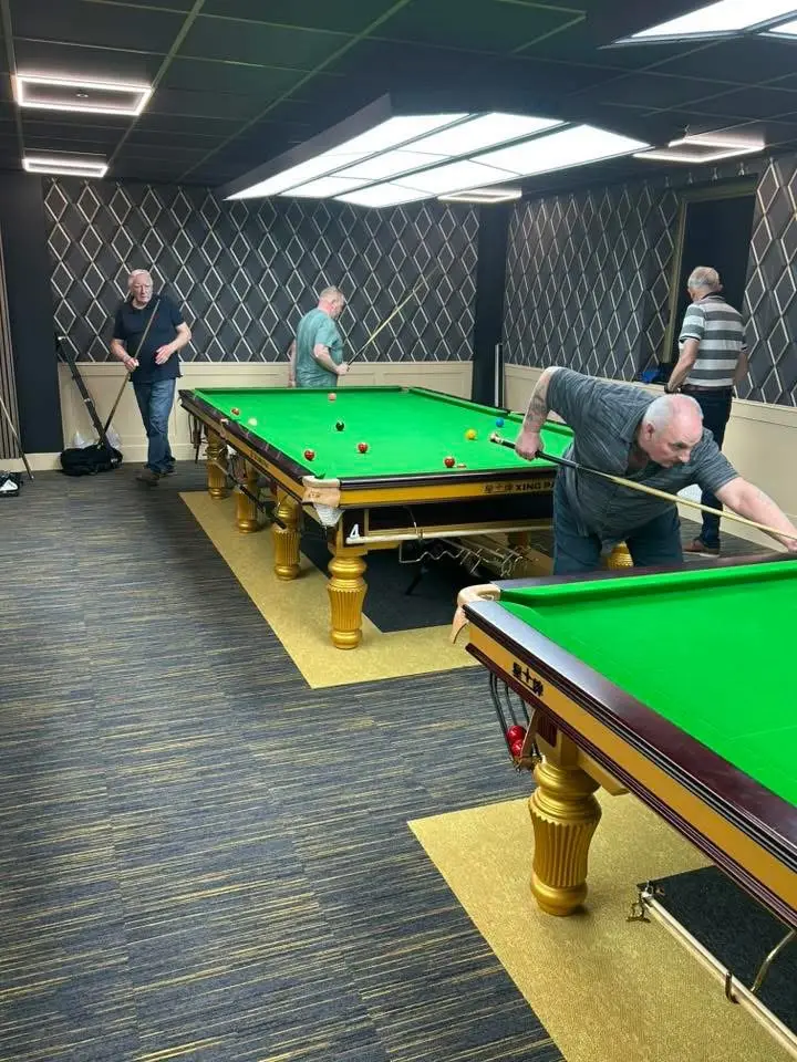 A player bent over the shot in the foreground, with another match under way behind